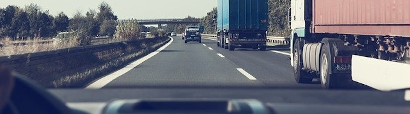 Image of large trucks on a road through a car’s windshield, representing the serious nature of accidents with commercial vehicles and the need for a WV truck accident lawyer to help you recover if you are injured in these accidents.